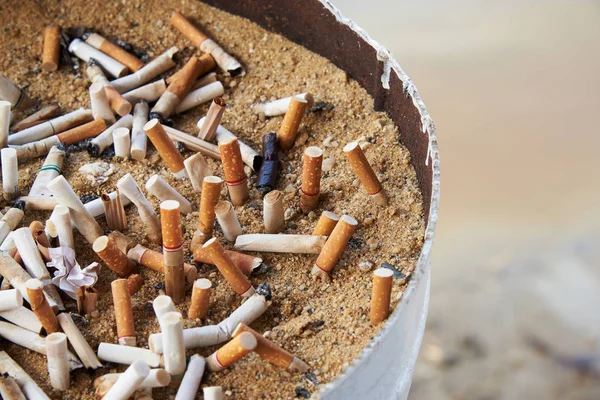 Muchas colillas de cigarrillos cerradas en el cenicero de arena — Foto de Stock