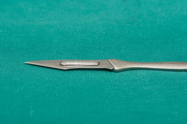 Opearating odasında yeşil bir kılıf üzerinde Cerrahi bıçak — Stok fotoğraf