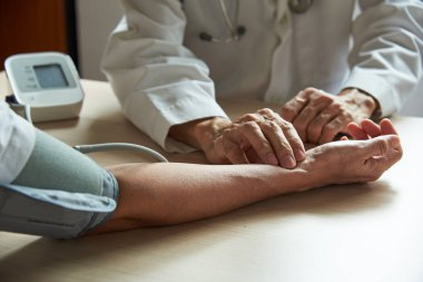 Tıbbi ofiste hastanın hayati belirtilerini inceleyen bir doktor