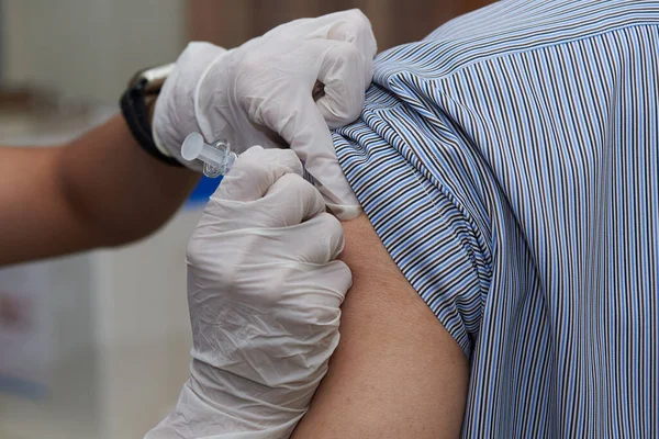 A nurse injecting  a dose of influenza vaccine at patient arm