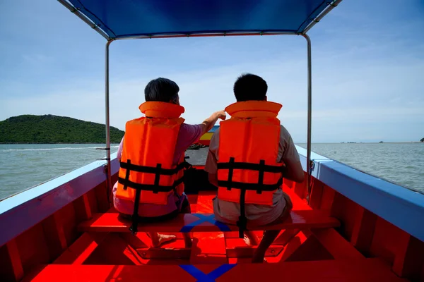 Two Asian tourists wearing life jacket on longtail boat with social distancing maker at the seats