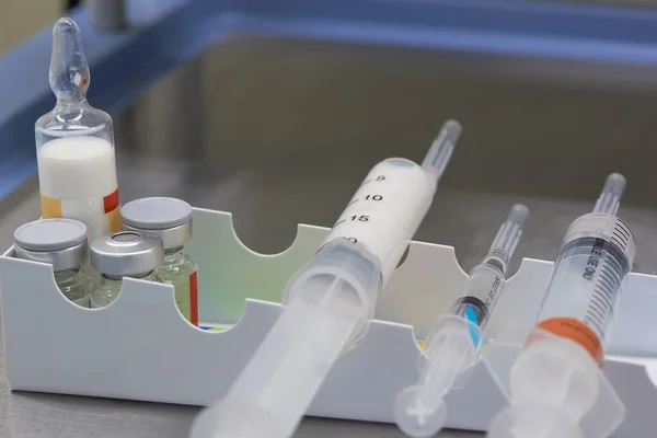 Şırıngada beyaz anestezi ilacı ve ameliyat odasındaki masada ilaçlar.