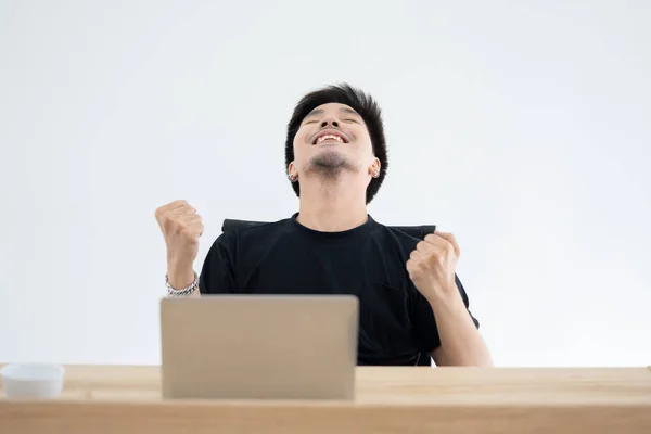 Asian Guy Raise His Arm Up Celebrating His Work Success in Front of His Laptop