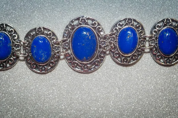 Vintage silver bracelet with natural stone, blue lapis lazuli background.