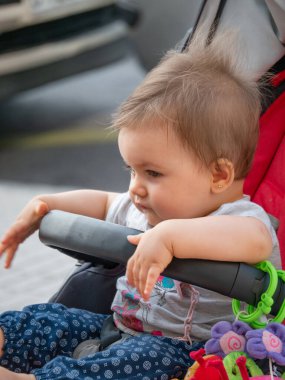 Bebek arabasında şirin bir bebek var. Sokakta, izliyor..