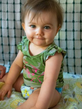 Sevimli küçük bebek. Oturup izliyor, önüne bakıyor..