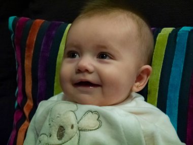 Küçük şirin beyaz bir bebek. Kanepede oturuyor, gülümsüyor..