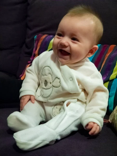 かわいい白人の赤ちゃん 彼女はソファに座って笑っている — ストック写真