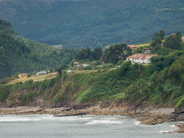 Sahille dağ arasında bir sürü ev. Bulutlu bir gün ve deniz sessiz..