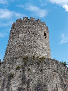 Taştan yapılmış, harabeye dönmüş bir ortaçağ kulesi. Güneşli bir gün ve gökyüzü mavi..