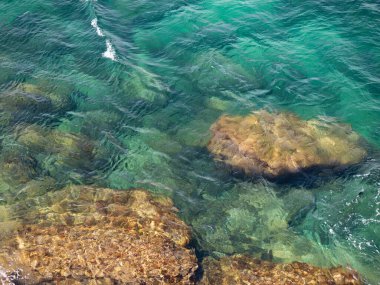 Deniz suyunun altındaki kayalar. Kristal sudaki dalgaların arasından görülebilirler..