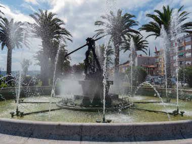 Güneşli bir günde çeşme çalışıyor. Şehir arka planında akan ve damlayan birçok su akıntısı vardır..