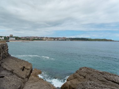 Cantabrian deniz manzarası, bulutlu bir gökyüzü. Ön planda bazı kayalar ve arka planda kıyıdaki bazı köyleri görebilirsiniz..