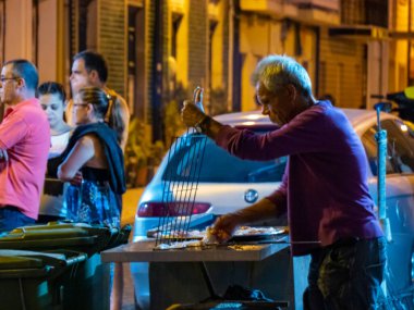 Sao Pedro da Afurada, Vila Nova de Gaia, Portekiz; 11 Ağustos 2017. Bu köyde her gün bir balıkçı sokakta balık pişirirken bazıları yemek sırasını bekliyor.