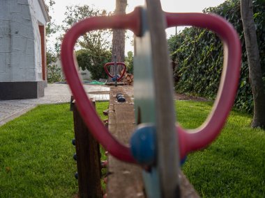 Kırsal bir evin bahçesindeki çimenlikte bulunan tahta çocuk testere.