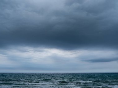 Bulutlu bir günde deniz manzarası, bir sürü gri bulutlar ve sakin bir deniz, ufuktaki çizgiyi görüyor.