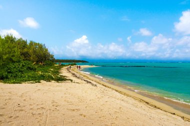 güneşli bir günde kumlu plaj görünümü, bulutlar ile mavi gökyüzü