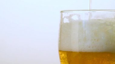 hafif bira beyaz bir arka plan üzerinde köpük yakın çekim ile bir bardağa dökülür