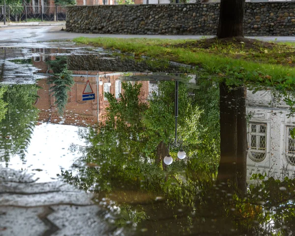 Yağmur sonrası su birikintilerindeki şehir binalarının ve sokak ışıklarının yansıması