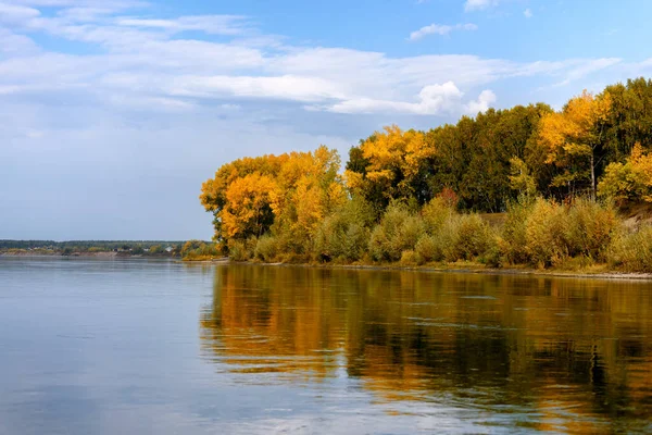 landscape on the river, blue sky with clouds, Bank edge with autumn forest