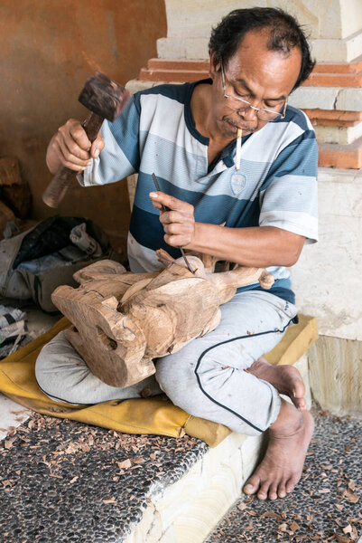 Bali, Indonesia - August 13th 2018: Woodcarver in Mas village in Ubud. Woodcarving is very famous in some villages of Bali.