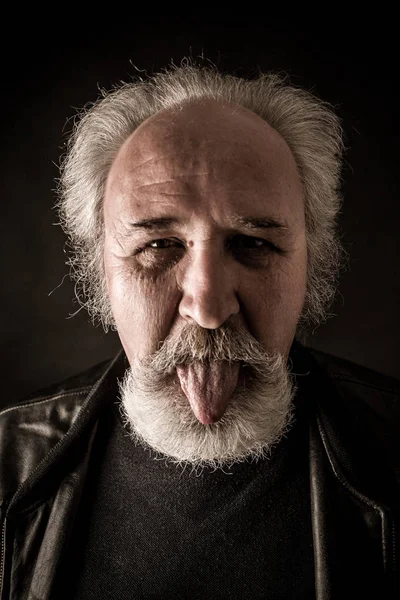 Grumpy Senior Manshowing Tongue Dark Background — Stok Foto