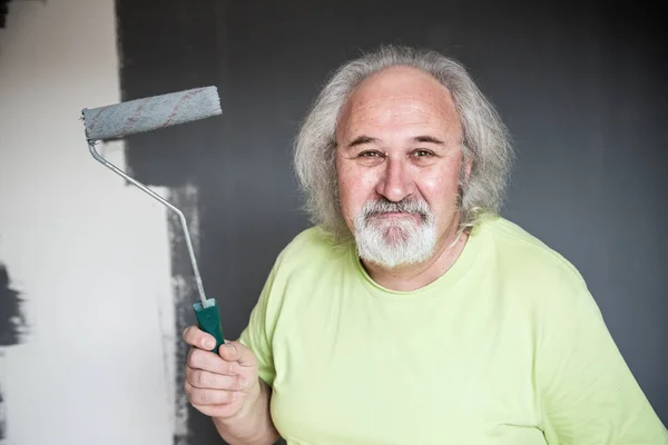 Engraçado homem sênior pintando a parede — Fotografia de Stock