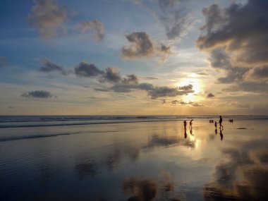 Bulutlar ıslak kum yansıması ile gün batımında yansıtılmış Bali beach