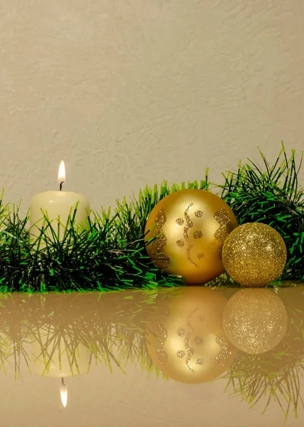 パターンのゴールドクリスマスボール グリーンティンセル完全な反射を持つガラス表面に白い燃えるろうそく — ストック写真