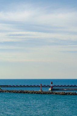 Limanda uçsuz bucaksız deniz ufku. Gemi iskelesi, kırmızı deniz feneri, rıhtım ve dalgakıran. Sosyal ağ hikayesi için dikey çerçeve. Beklenti konsepti