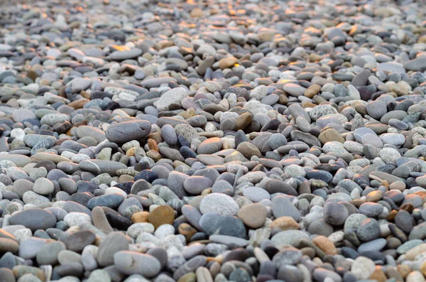 Große Kieselsteine am Strand, mit dem grellen Licht der roten Sonne — Stockfoto