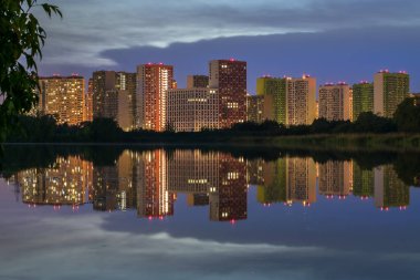 Gece ışıkları ışığında deniz nehri kıyısında inşaat halindeki yeni konut kompleksi suya vinçlerle yansıtılıyor.