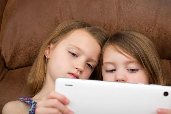 Zwei Mädchen Beobachten Gemeinsam Ein Tablet Stockfoto