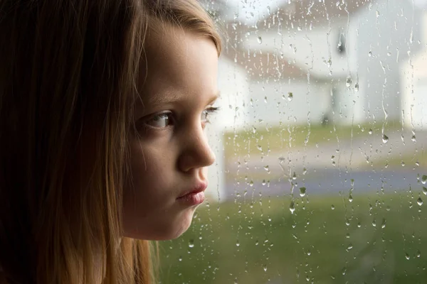 Trauriges Kleines Mädchen Starrt Aus Dem Verregneten Fenster Stockbild