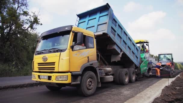 VINNYTSIA, UKRAINE - SEPTEMBER 10, 2018: unloading asphalt into the asphalt paver — Stock Video