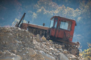 arka plan ağaç üzerinde taş bir höyük üzerinde eski kırmızı traktör