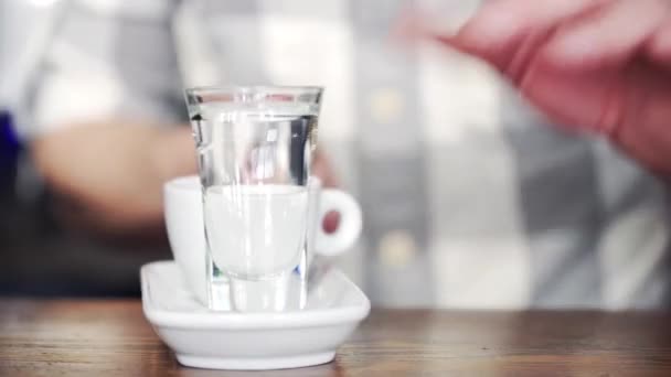 バーマンは 木製のカウンターに一杯のコーヒー ティー スプーン いくつかの砂糖と水のグラスを置きます クローズ アップ — ストック動画