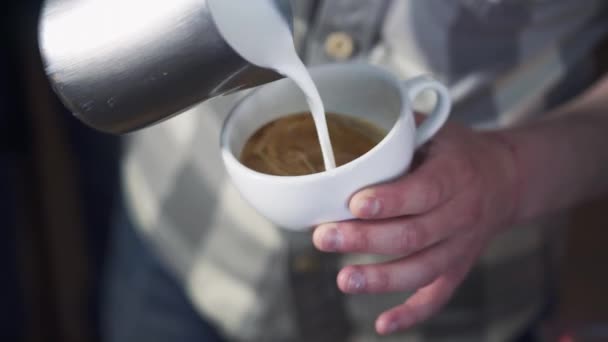 专业的咖啡师将牛奶泡沫倒在咖啡上 制成白杯 创造完美的卡布奇诺咖啡 并使一个不错的模式 — 图库视频影像