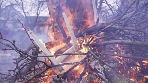 Παλιά καρέκλα στη φωτιά μαζί με ξηρά κλαδιά. Μεγάλη πυρκαγιά — Αρχείο Βίντεο