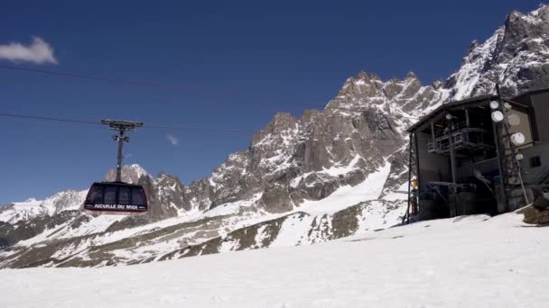 Kabina kolejki linowej przybywa na stacji wysoko w ośnieżonych górach w słoneczny dzień. Alpy górskie Aiguille du Midi — Wideo stockowe