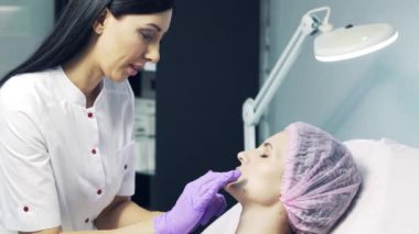 Estetik ofiste dudak büyütme konusunda bir hastaya danışan profesyonel güzellik uzmanı. Doktor kadını muayene ediyor.