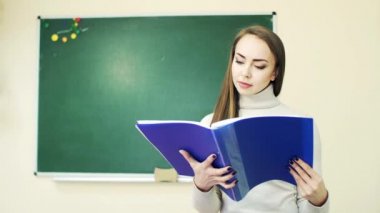 Yeşil okul tahtasına karşı sınıfta defter üzerinden öğrenci yapraklama