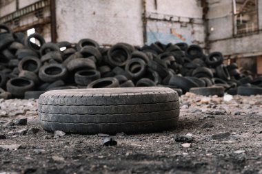 terk edilmiş bir fabrikanın zemininde yatan eski araba lastiği diğer lastiklere göre