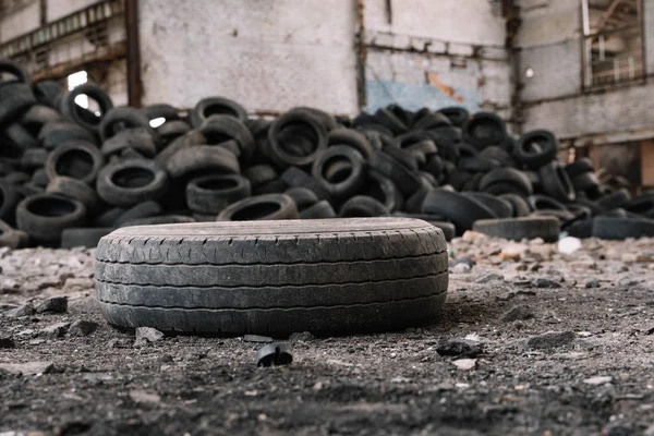 Vanha autonrengas makaa hylätyn tehtaan päällä verrattuna muihin renkaisiin — kuvapankkivalokuva