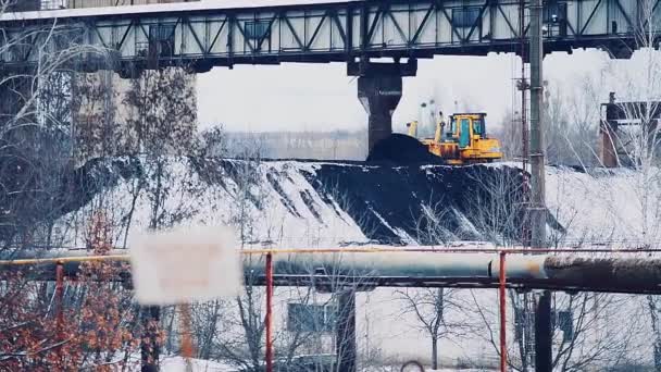 Bulldozer rocía una pila de carbón en el territorio de la central eléctrica. Carbón cubierto de nieve . — Vídeo de stock