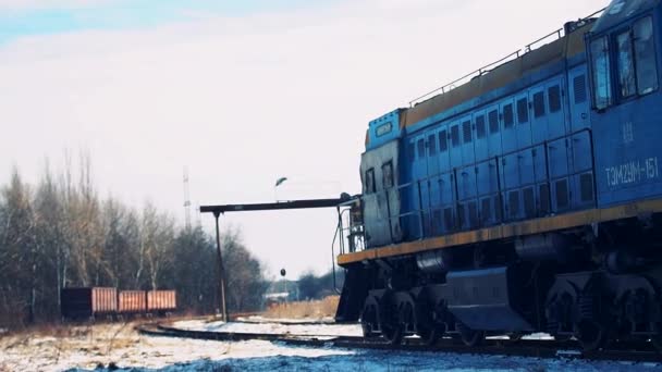 ディーゼル機関車は、雪に覆われた鉄道駅に貨物とワゴンを引っ張ります — ストック動画