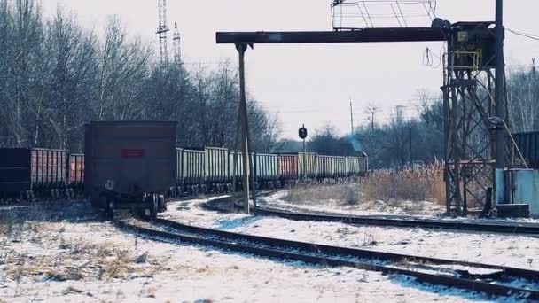 Дизельный поезд с грузовыми вагонами, движущимися вдоль заснеженной железнодорожной станции — стоковое видео