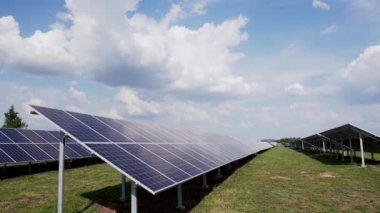 bulutlar ile mavi bir gökyüzüne karşı yeşil bir alanda güneş panelleri satır. Güneş Enerjisi Santrali.