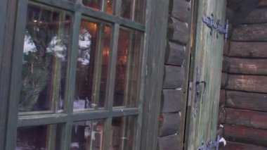 Elfler Noel Baba 'nın evinin ahşap kapısının arkasından dikizlerler.