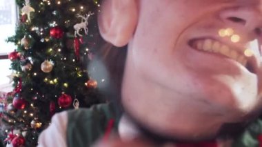 Noel Baba 'nın evindeki elf etrafta dolanıyor ve büyüteçle eğleniyor. Arka planda Yeni Yıl ağacı.